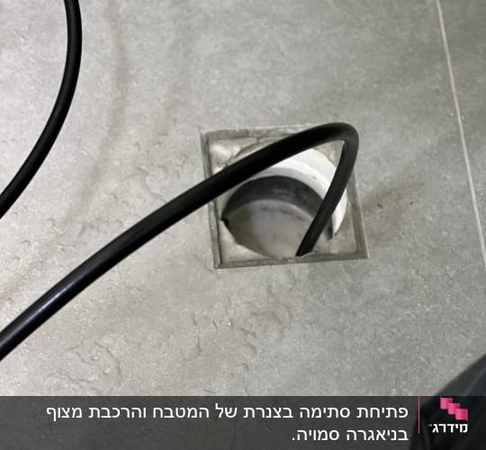 צינור שחור נכנס לניקוז ברצפה אפורה